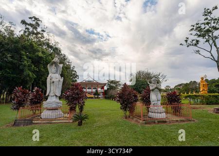 Des statues de pierre symétriques, dont la gracieuse Kuan-Yin, gardent le chemin d'entrée de la salle principale du temple bouddhiste Chen Tien à Foz do Iguaçu Banque D'Images
