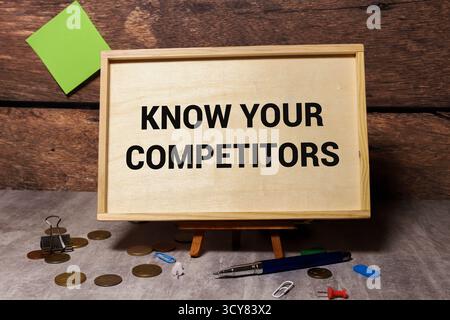 Vue de dessus d'une carte de visite avec du texte CONNAÎTRE VOS CONCURRENTS, stylo, trombones sur un fond coloré. Concept commercial. Banque D'Images