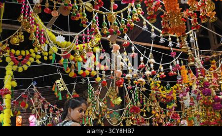 Mumbai, Inde. 17 octobre 2025. Une femme commerçante (l) est vue dans son magasin 'toran' (porte décorative suspendue) dans les rues devant Diwali, festival hindou des lumières à Mumbai. Diwali est la fête des lumières célébrée par les hindous à travers le pays. Les gens nettoient leur maison, dessinent un rangoli (une forme d'art traditionnel indien où divers motifs sont faits sur le sol), achètent des lanternes, de nouveaux vêtements, des bonbons et des collations. Ils éclairent leurs maisons avec des lampes en terre marquant la victoire de la lumière sur les ténèbres. Crédit : SOPA images Limited/Alamy Live News Banque D'Images