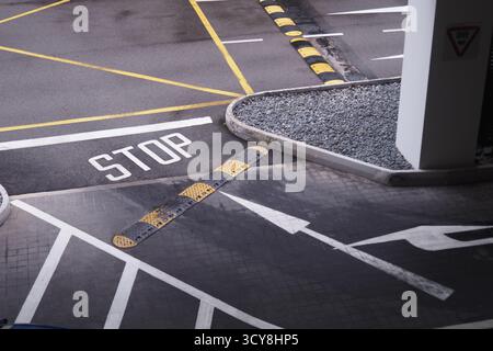 Panneau d'arrêt dans l'aire de stationnement avec des voies et des bordures de trottoir balisées Banque D'Images