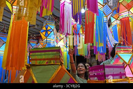 Mumbai, Inde. 17 octobre 2025. Une femme commerçante montre une lanterne au client (pas sur la photo) devant Diwali, festival hindou des lumières dans un marché aux lanternes dans les rues de Mumbai. Diwali est la fête des lumières célébrée par les hindous à travers le pays. Les gens nettoient leur maison, dessinent un rangoli (une forme d'art traditionnel indien où divers motifs sont faits sur le sol), achètent des lanternes, de nouveaux vêtements, des bonbons et des collations. Ils éclairent leurs maisons avec des lampes en terre marquant la victoire de la lumière sur les ténèbres. (Photo par Ashish Vaishnav/SOPA images/SIPA USA) crédit : SIPA USA/Alamy Live News Banque D'Images