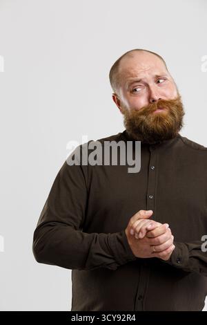 Photo de pensive homme chauve en chemise brune avec du gingembre beard avec un fond gris vide Banque D'Images