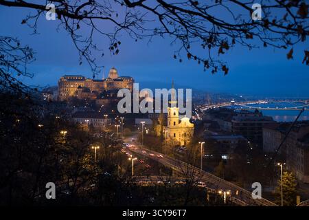 Budapest vue en soirée avec le château de Buda, l'église Sainte-Anne illuminée et les feux de circulation le long de la rivière Danube. Banque D'Images