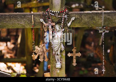 Croix religieuses et chapelets suspendus à une croix en bois. Symbole de foi et de spiritualité. Lieu de pèlerinage chrétien avec des signes de dévotion et de prière. Banque D'Images