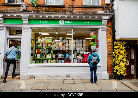 Femme debout devant la librairie Oxfam regardant l'affichage dans la vitrine, ville de York Banque D'Images