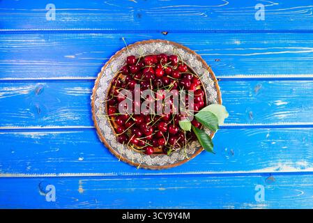 Cerises rouges mûres dans une plaque de métal sur une table en bois bleu. Cerise fraîche récoltée. Fruits biologiques Banque D'Images