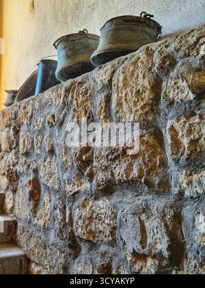 vieux pots en métal debout sur un mur de pierre. le mur est en pierre brute. style historique rustique Banque D'Images