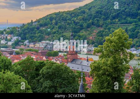 Vue panoramique sur Heidelberg avec la vieille ville, la tour de l'église proéminente et les collines verdoyantes au crépuscule, avec un éclairage tamisé améliorant le guichet automatique serein Banque D'Images