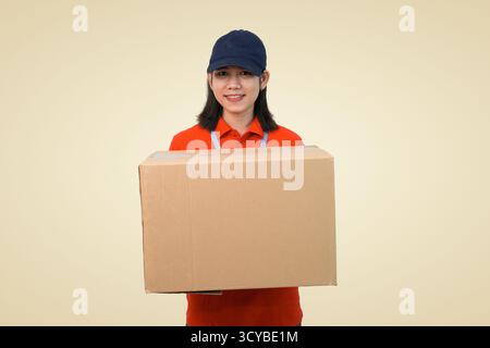 heureux livreur de femme en uniforme rouge tenant une grande boîte en carton pour l'expédition Banque D'Images