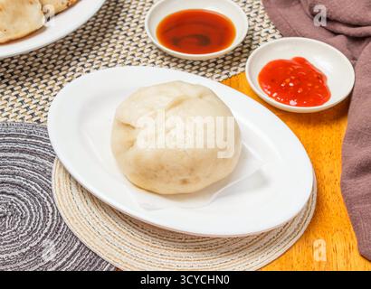 Petits pains au poivre et au porc cuits à la vapeur avec sauce servie dans une assiette servies en servies dans une serviette isolée vue latérale des dim sum chinois Banque D'Images
