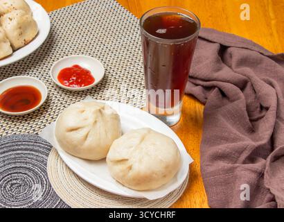 2 petits pains cuits à la vapeur avec sauces trempées et un grand verre de thé glacé isolé sur la serviette vue latérale de la nourriture dim sum de taiwan Banque D'Images