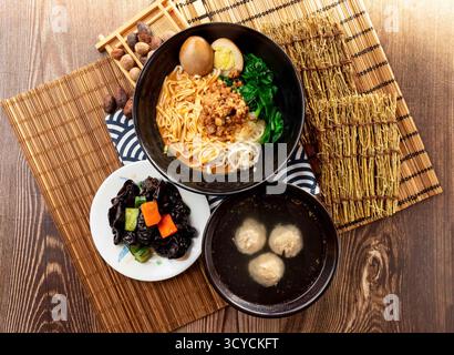 Nouilles en pâte de sésame avec champignon noir, soupe aux boulettes de viande, viande de porc hachée, œuf conservé et baguettes servies dans une assiette isolée sur la serviette vue de dessus Banque D'Images