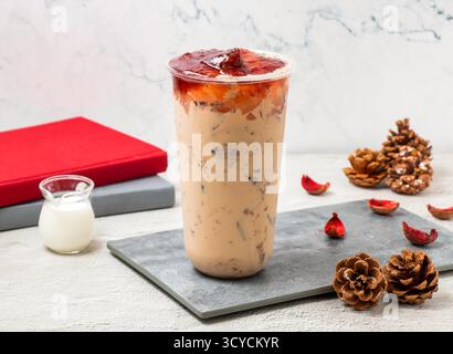 Thé glacé au lait de fraise servi dans un verre jetable isolé à bord vue latérale de la boisson glacée taïwanaise Banque D'Images