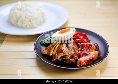 Canard rôti et Char Siu avec riz et œuf à la coque salé servis dans une assiette isolée sur la table vue en gros plan de la nourriture de Hong Kong Banque D'Images