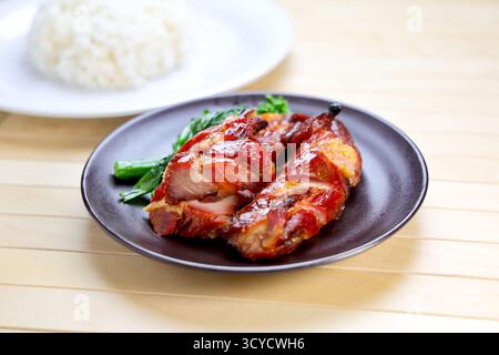 Porc grillé avec riz servi dans une assiette isolé sur la table vue de côté de la nourriture de Hong Kong Banque D'Images