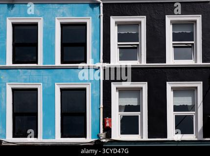 La façade du bâtiment présente des murs bleus et noirs distincts. La structure révèle de multiples fenêtres, améliorant l'atmosphère urbaine vibrante. Maison britannique Banque D'Images
