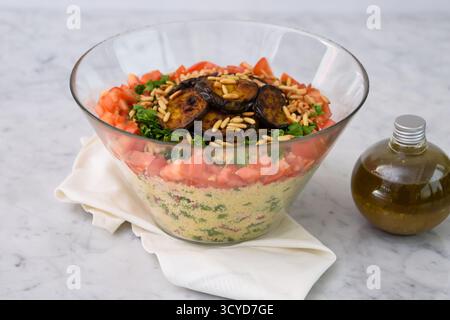 Salade de couscous méditerranéens frais avec aubergines grillées avec couscous, tomates, persil, tranches d'aubergines grillées et pignons de pin grillés avec un Banque D'Images
