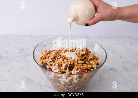 Vibrante salade de noix de cajou au brocoli dans un bol en verre sauce crémeuse est versée dessus, comprend des bouquets de brocoli, des noix de cajou croquantes, des carottes râpées, et re Banque D'Images