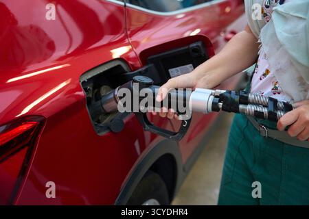 Personne ravitaillant la voiture rouge à la station-service hydrogène pétrole et crise des prix du gaz Banque D'Images