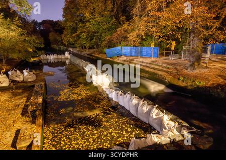 Munich, Allemagne. 18 octobre 2025. Des dizaines de sacs de sable et une machine de construction se trouvent au fond de l'Eisbach partiellement drainé dans le jardin anglais. Le surf sur l'Eisbach n'est actuellement plus possible car le balayage annuel du ruisseau a commencé à nettoyer le fond. La vague d'Eisbach est un hotspot pour les surfeurs de loisirs. Crédit : Peter Kneffel/dpa/Alamy Live News Banque D'Images