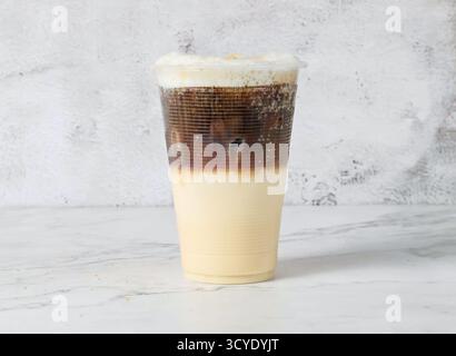 Boisson glacée de café glacé en couches kopi cino servie dans une tasse en plastique isolée sur fond de marbre vue latérale de la boisson de Singapour Banque D'Images