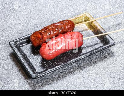 Brochettes de saucisses grillées authentiques servies dans un plat de plateau isolé sur fond de pierre vue latérale de la nourriture de Kong Banque D'Images