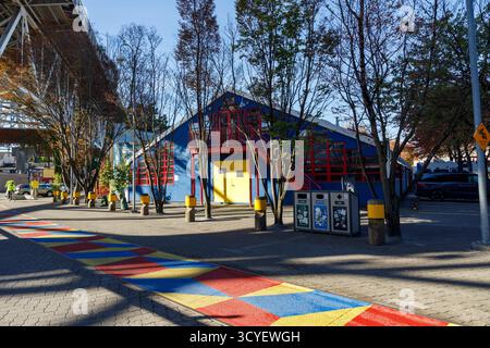 Vancouver, Canada - Oct 6,2025 : bâtiment coloré Granville Island avec murs bleus, éléments structurels rouges, porte jaune, chemin géométrique peint, a Banque D'Images