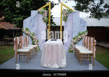 Installez des chaises et des décorations de table pour une séance de cérémonie pour prononcer un vœu de mariage tenu dans un jardin. Banque D'Images