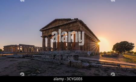 La lumière dorée du soir baigne les anciens temples grecs de Poséidon et Hera à Paestum, Campanie, Italie. Les tons chauds du coucher de soleil soulignent le Dor Banque D'Images