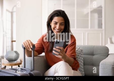 Joyeuse jeune femme touristique latine tapant sur smartphone Banque D'Images