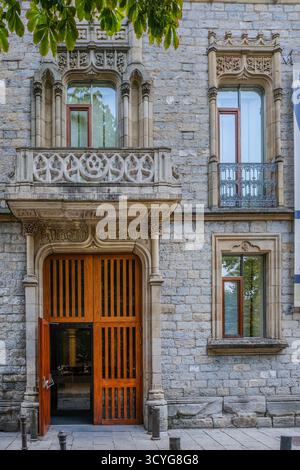 Façade historique en pierre avec grande porte d'entrée en bois et balcon en pierre orné, avec détails architecturaux néogothiques Banque D'Images