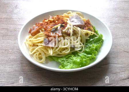 spaghettis frits sauce à la crème blanche cabonara garniture tranche de bacon de porc croustillant et de laitue dans l'assiette Banque D'Images