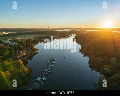 Vue aérienne élevée par drone le long de Djurgårdsbrunnsviken vers la tour Kaknästornet pendant un lever de soleil éclatant sur Stockholm, Suède Banque D'Images