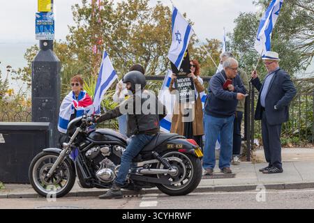 Southend on Sea, Royaume-Uni. 19 octobre 2025. Les manifestants à Southend-on-Sea tiennent des drapeaux israéliens et britanniques à côté du front de mer. Un panneau indiquant « PLUS JAMAIS, C’EST MAINTENANT ! » est visible, faisant référence à l'antisémitisme. Un motocycliste est garé au premier plan. Des militants de Southend et des régions avoisinantes s’unissent pour soutenir la paix et la justice pour le peuple palestinien. Penelope Barritt/Alamy Live News Banque D'Images
