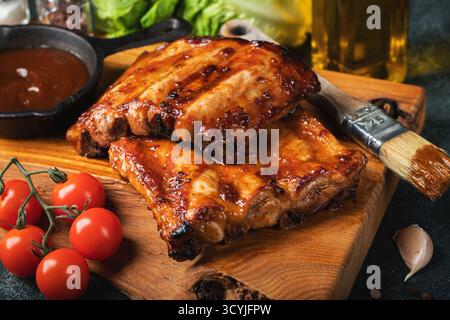 Côtes de rechange grillées chaudes épicées d'un barbecue d'été servies avec un piment chaud et des tomates fraîches Banque D'Images