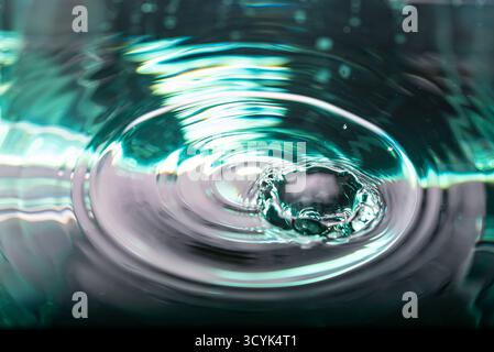 367.macro photographie capture l'éclaboussure dynamique et les ondulations rayonnantes créées par une goutte d'eau.L'image est dominée par turquoise profonde, bleu-vert, a Banque D'Images