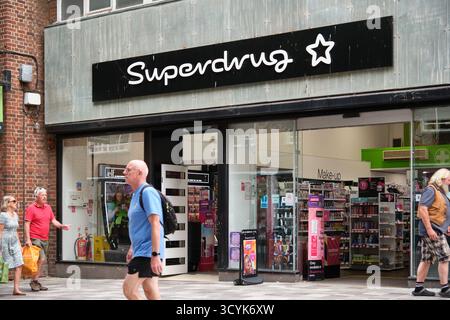 Les gens passant devant la devanture d'un magasin Superdrug situé sur une rue animée de Canterbury avec des affichages visibles Inside.Canterbury, Kent Banque D'Images
