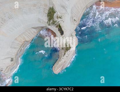 Vue aérienne spectaculaire du cap Drastis, Corfou, Grèce, avec des falaises blanches frappantes, des formations érodées uniques et la mer Ionienne turquoise vibrante. Banque D'Images
