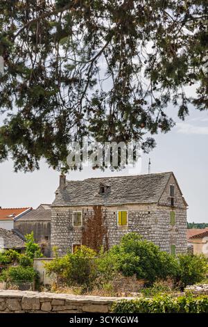 Une charmante maison en pierre dans un village calme, avec des murs ensoleillés, des volets colorés et du lierre grimpant. Entouré de verdure et autres cottag Banque D'Images
