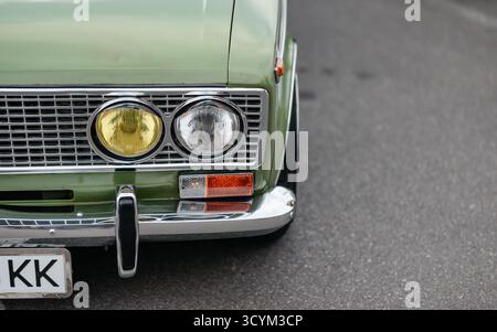 Phare de voiture des années 1970 - berline VAZ 2103 classique sur une route. Vue de face rapprochée de Lada verte. Banque D'Images
