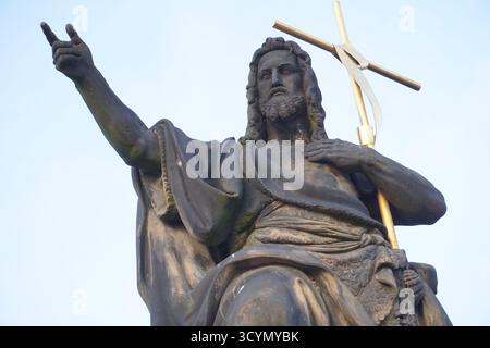 Gros plan frontal d'une statue en grès de Jésus Christ, seigneur miséricordieux et sauveur, tenant une croix d'or sur le pont Charles, Prague, République tchèque Banque D'Images