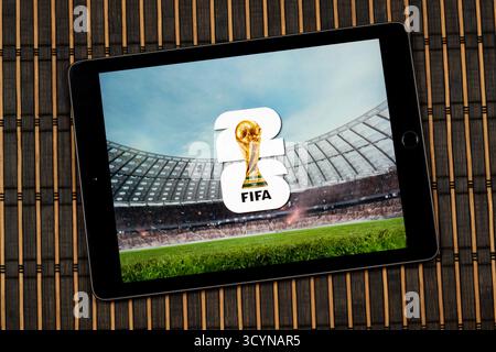 Gros plan sur un iPad avec le logo de la Coupe du monde de la fifa 2026 sur un stade flou et un fond en bois Banque D'Images