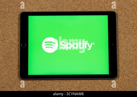 Gros plan sur un iPad avec le logo musical numérique spotify blanc sur un écran vert et un fond en liège Banque D'Images