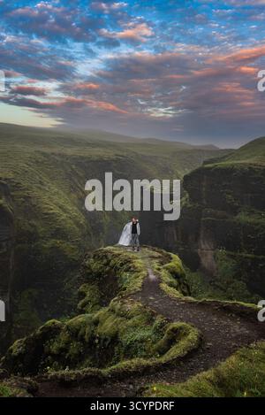 Couple sur une falaise moussue au canyon de Fjadrargljufur, au sud de l'Islande Banque D'Images