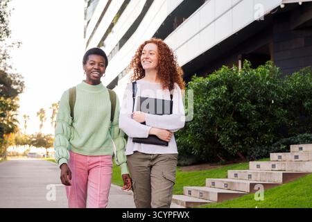 deux jeunes étudiants souriants et marchant dans la rue Banque D'Images