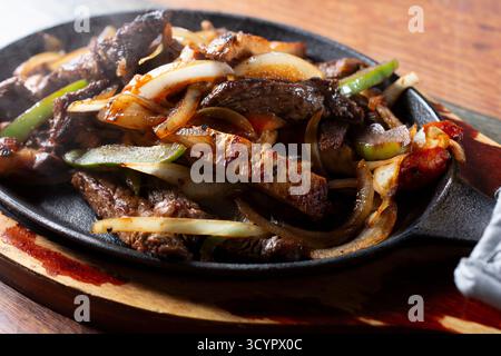 Une vue rapprochée d'une commande de fajitas de bœuf et de poulet grésillantes. Banque D'Images