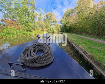 Vue depuis la proue d'un bateau étroit amarré dans le paysage rural anglais sur le canal de la voie navigable britannique avec un ciel bleu en automne saison d'automne Banque D'Images