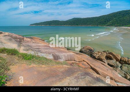 Plage de Guaiuba, Guaruja SP, Brésil. Journée ensoleillée sur la petite baie avec mer tranquille. Image des loisirs et du tourisme sur la côte de Sao Paulo. Collines couvertes Banque D'Images