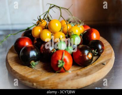 Une assiette en bois, pleine de différentes variétés de tomates Banque D'Images