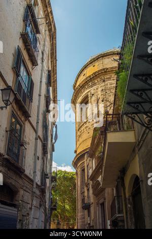 Une rue étroite ombragée à Palerme, Italie. Un effet de « canyon urbain » avec de hauts bâtiments de chaque côté. Au bout de la rue, une église baroque abside Banque D'Images